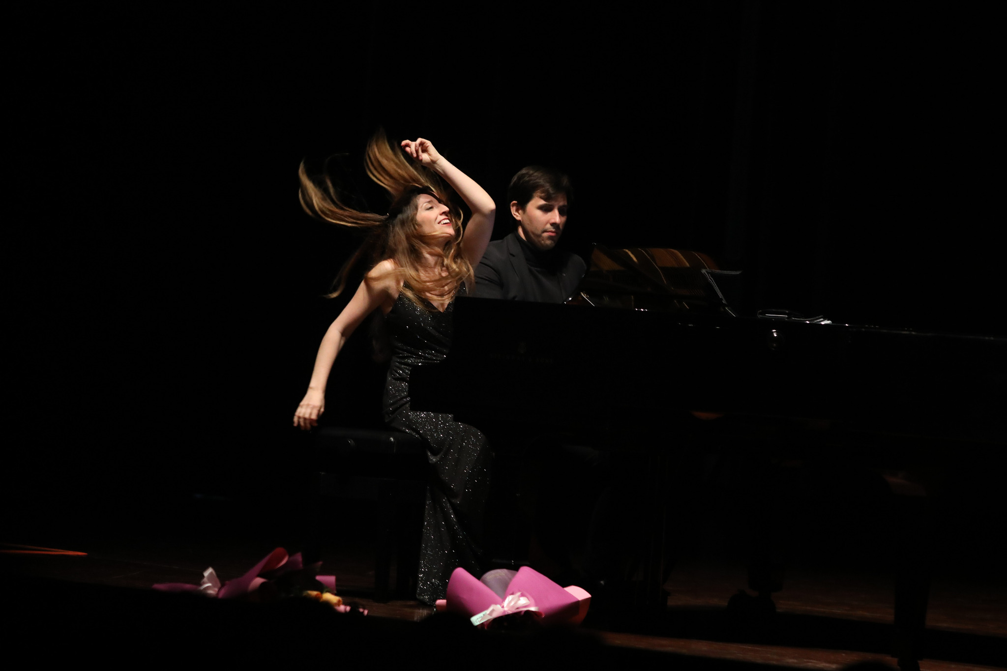Anton y Maite junto al piano sobre un escenario oscuro.
